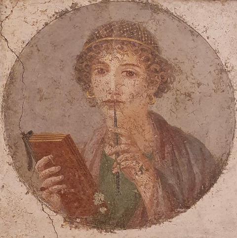 一幅挂在裂缝墙上的壁画, 一个穿着蓝绿相间长袍，卷发的女人, 一只手拿着书，另一只手拿着书写工具. 