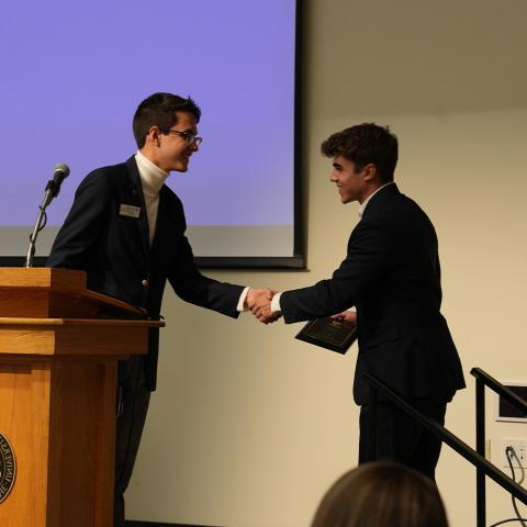 Two students shaking hands, receiving award.