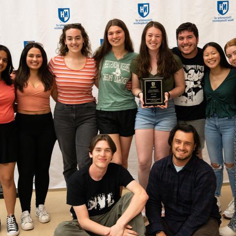 Student org group standing holding award plaque.