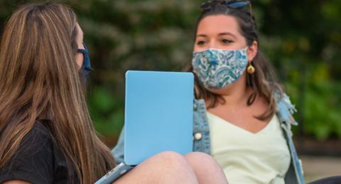 学生们戴着口罩在草坪上社交