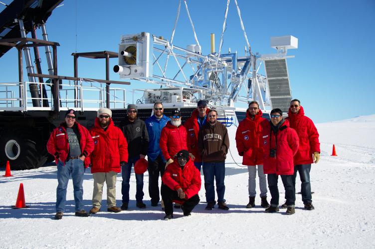 南极洲的一组研究人员站在一架大望远镜前.